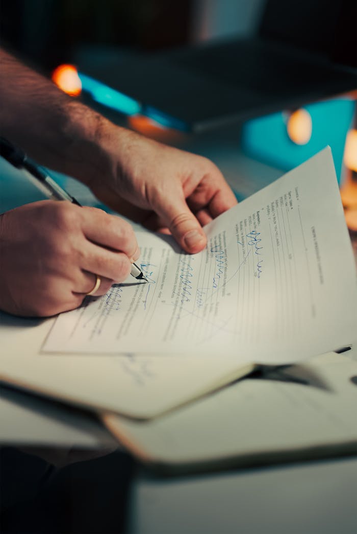 Close-up of hands signing a business contract in an office environment. Ideal for legal and finance themes.